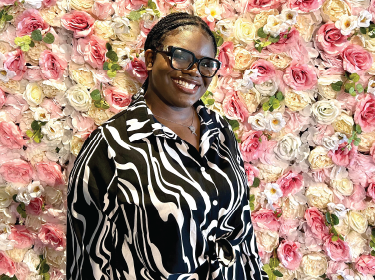 student standing in front of floral backdrop